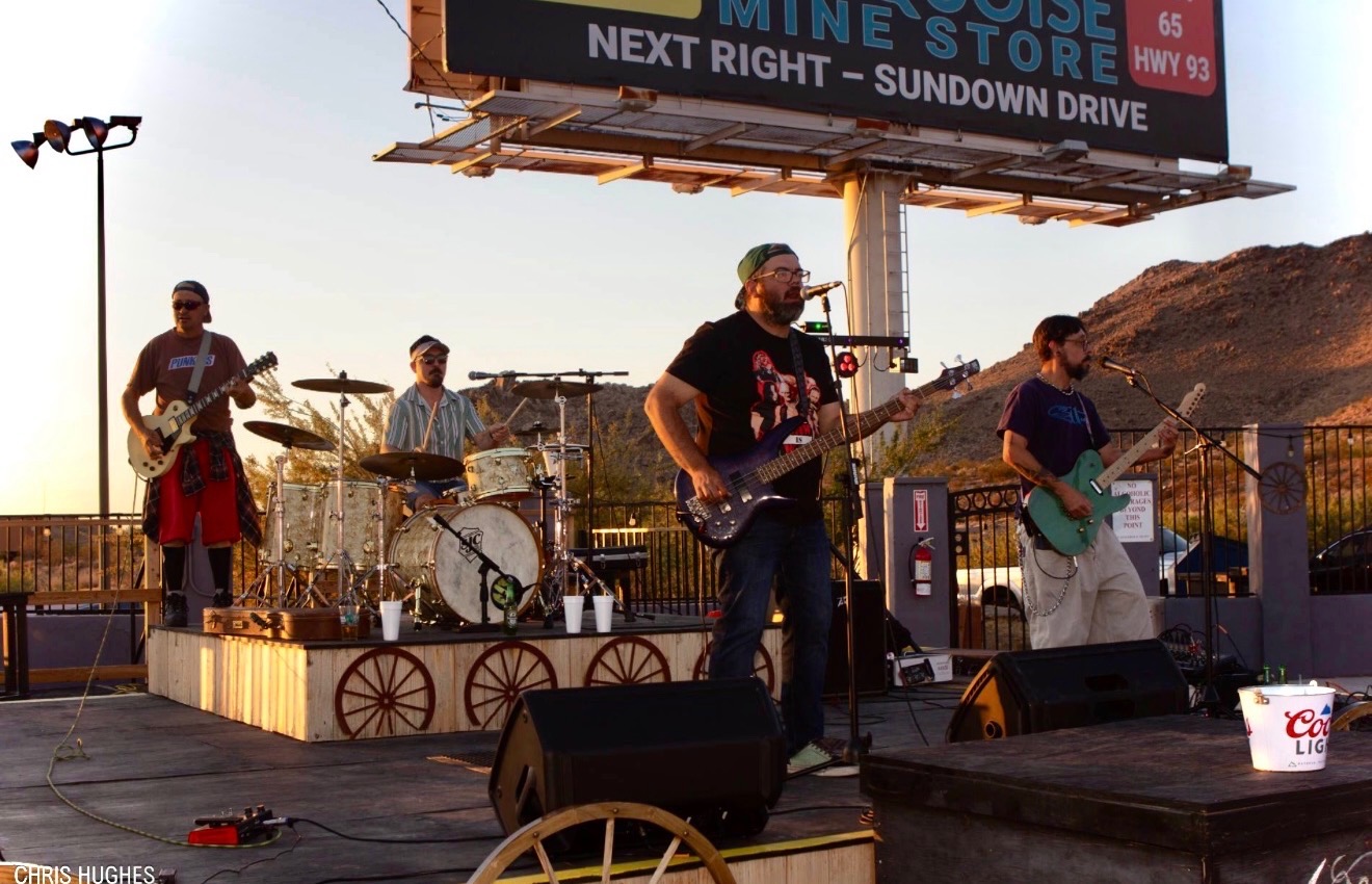 Live band on the Castle Rock stage at golden hour beside US Hwy 93