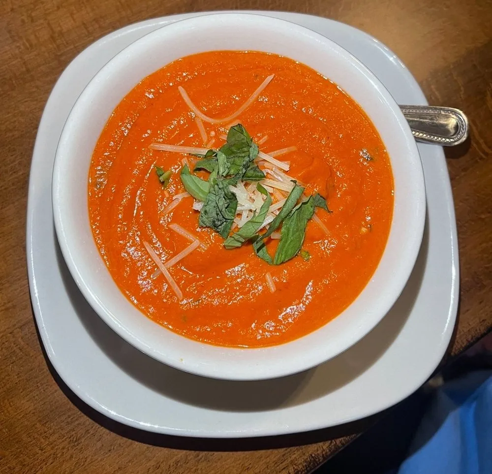 Creamy tomato basil soup topped with fresh basil and parmesan