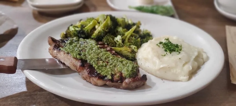 Grilled New York strip topped with chimichurri, roasted broccoli and mashed potatoes